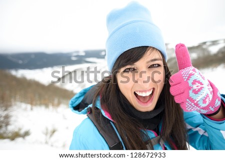 Fun woman hiking on winter mountain success with thumbs up. Female hiker achievement face expression outdoors.