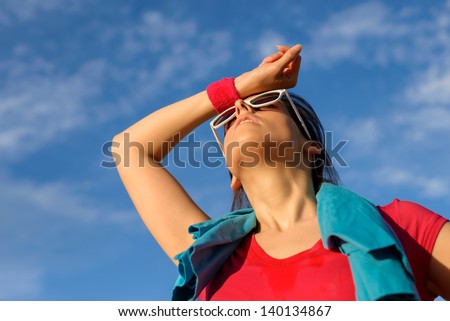 Athlete woman wiping the sweat from his brow with a wristband. Tired fitness caucasian girl sweating after exercising on summer outdoor.