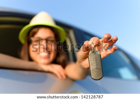 Girl showing new car keys after buying it. Travel and rental concept.