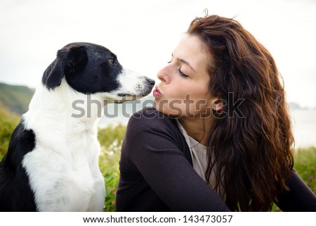 Dog and woman cute kiss and friendship. Woman with her pet on travel to coast.