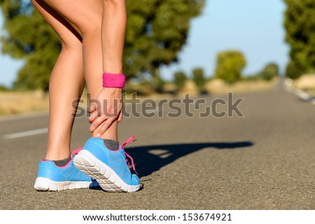 Sport running ankle sprain. Sportswoman touching painful twisted or broken ankle. Athlete runner training accident.