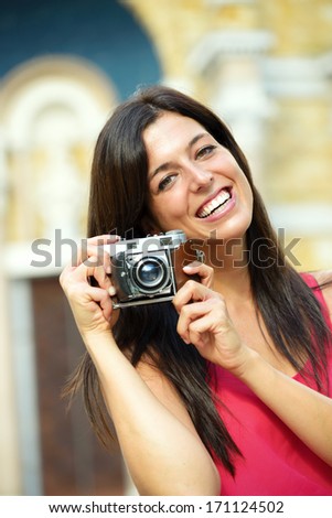 Woman on summer travel taking photo with retro film camera and smiling. Female photographer tourist on european cultural vacation.