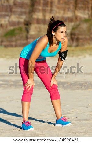 Exhausted fitness woman taking a break after running on summer at the beach.  Tired female runner resting.