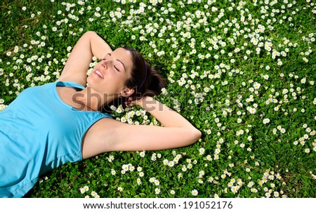 Female athlete resting and relaxing after workout. Woman lying down on grass and spring flowers. Healthy lifestyle and happiness concept.