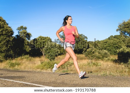 Female athlete on running workout in country road . Fitness sporty female runner training on summer.