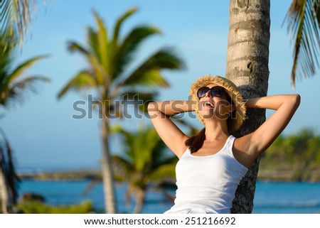 Woman on caribbean travel enjoying under tropical palm trees. Happy brunette enjoying vacation and tranquility.