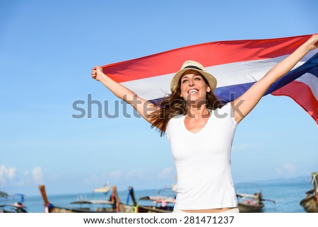 Happy woman having fun at Krabi beach with Thailand flag. Beautiful brunette enjoying travel to Asia.