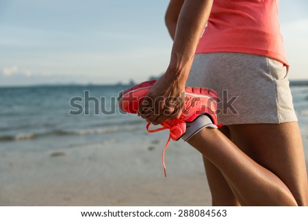 Running and healthy lifestyle concept. Runner footwear close up. Woman warming up for training at the beach.
