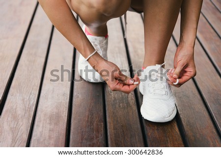 Woman lacing fitness and sport footwear for healthy lifestyle concept. Female athlete getting ready for workout training and challenge.