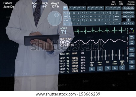 A Physician uses a tablet computer while standing behind a floating computer display.