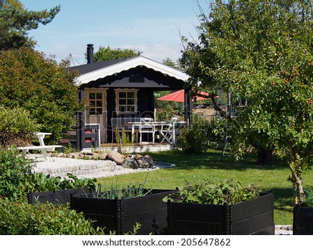 Wooden bungalow cabin painted black in a beautiful garden