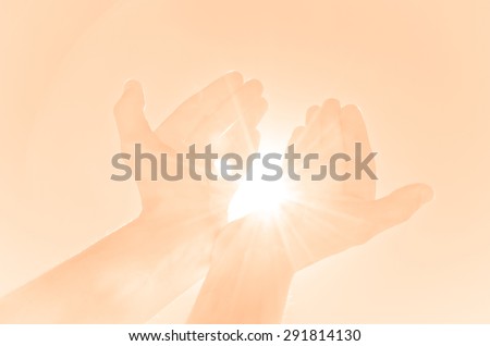 Hands holding the sun or offering light against a plain pinkish background
