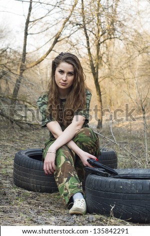Beautiful girl in military uniform at the wheel tires