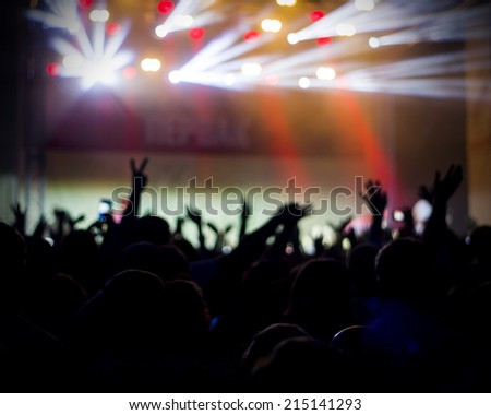 Photo of young peofans applauding to famous music band, nightlife, DJ on the stage in the club, crowd dancing on dance-floor, night performanceple having fun at rock concert,
