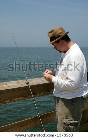 A man baiting a fishing hook on a fishing pier.