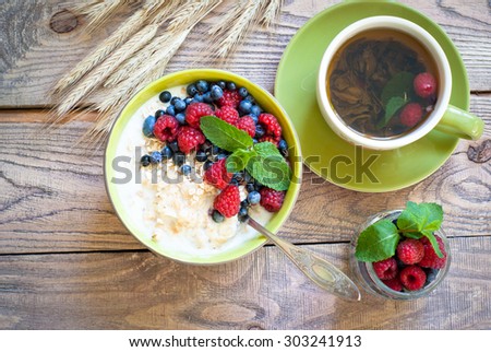 Healthy breakfast - oatmeal with berries and a cup of green tea