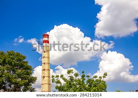 High industrial chimney in brickyard factory with cloudy sky