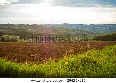 Arable land in a hilly landscape at morning sunrise with moody sky