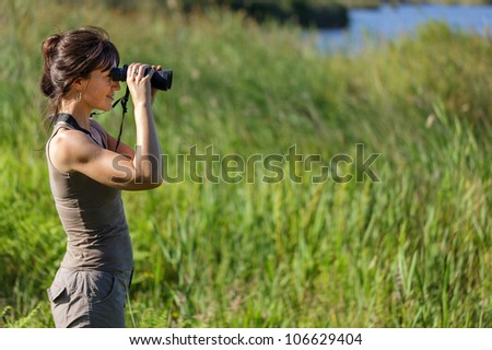 woman watching wildlife with binoculars in swamp area