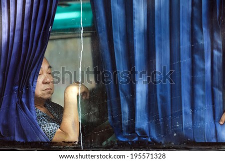 CHINATOWN,BANGKOK,THAILAND, DECEMBER 16 : portrait of a chinese man looking at the dirty bus window behind the curtains in Bangkok, Thailand on December 16, 2012