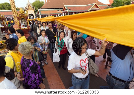LAMPHUN, THAILAND, DECEMBER 31, 2014: Thai people are holding a long sacred cloth, in procession around the Wat Phra That Hariphunchai temple for celebrating the new year in Lamphun, Thailand