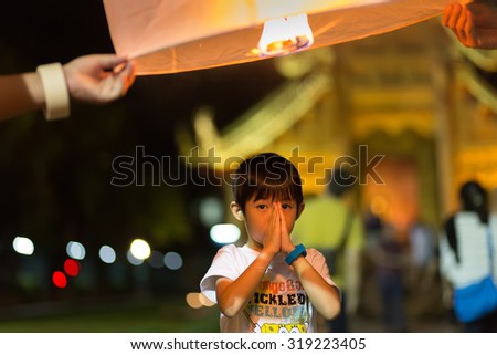CHIANG MAI, THAILAND, JANUARY 1, 2015 :  A little boy is praying and making a wish for the new year while a floating lantern is launched to the sky in Chiang Mai, Thailand