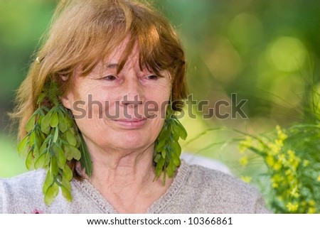outdoors portrait of smiling beautiful senior woman with earrings of leaves