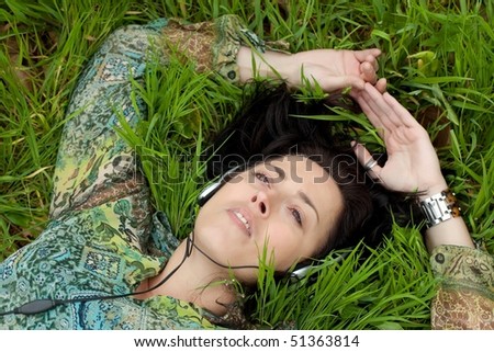 woman lying on back listening music on grass