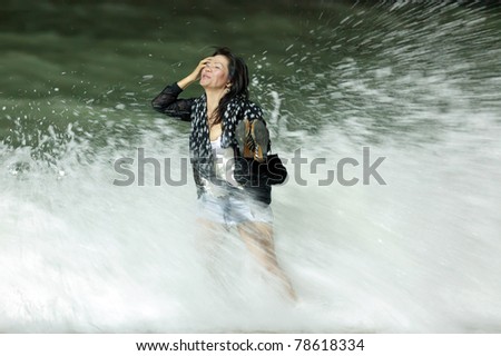 courageous asian woman getting dressed standing in  rough breaker at night, motion blurry