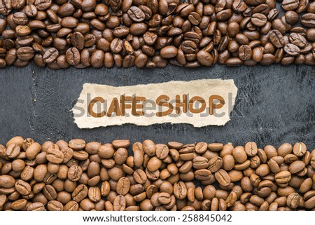 Coffee beans with Cafe Shop label on black wooden background.