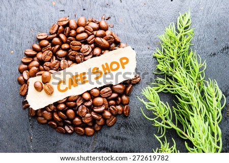 Coffee beans with Cafe Shop label on black wooden background. Photo in vintage color tone style.