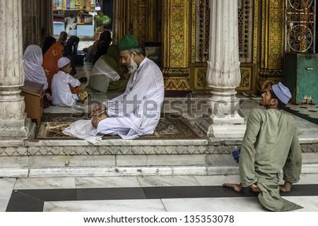 DELHI, INDIA - AUGUST 06: An unidentified man prays whilst disabled beggar waits patiently for alms at the beautiful mosque on August 06, 2011 in Nizamuddin, Old Delhi, India.
