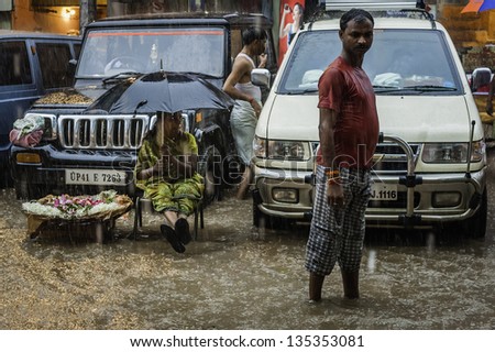 VARANASI, INDIA - AUGUST 11: monsoon rain and flash flood yet woman with only an umbrella continues to sell her flowers and garlands on the street on August 11, 2011 in Varanasi, Uttar Pradesh, India.