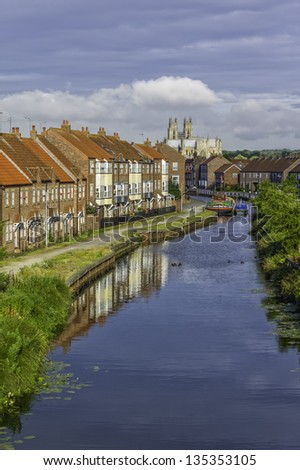 BEVERLEY, UK - JULY 29, 2012: vintage river barge moored on the beck flanked by houses with Beverley Minster as backdrop on July 29, 2012 in Beverley, Yorkshire, UK