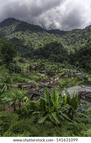 Tawang, Arunachal Pradesh, India. View of a village, shanty town, alongside the main road between Assam and Tawang showing the high mountains,forests, houses on stilts, and other vegetation.