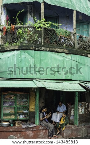 KOLKATA, INDIA - AUGUST 17: family enjoys an early morning discussion outside their colourful ex-colonial house and next to their small sweet shop on August 17, 2011 in Kalighat, Kolkata, India.