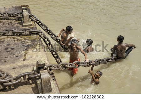 KOLKATA, INDIA - AUGUST 19: Young men bathe in the Hoogly next to the gian chains used to moor ferry boats on August 19, 2011 in Kolkata, India.