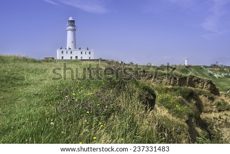 Flamborough, Bridlington, Yorkshire. The lighthouse flanked by the coastline and wild flowers on a  summer at Flamborough Head, East Riding of Yorkshire, UK.