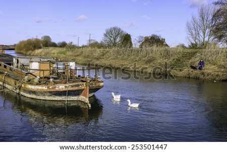 BEVERLEY, YORKSHIRE - FEBRUARY 17, 2015: Fishing on river Hull surrounded by derelict barges on a bright sunny afternoon on February 17, 2015 in Beverley, Yorkshire, UK.