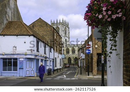 BEVERLEY, UK - JUNE 22, 2014: Man crosses Ladygate with view of shops and St Mary\'s Catholic church on a quiet Sunday morning on June 22, 2014 in Beverley, Yorkshire, UK.