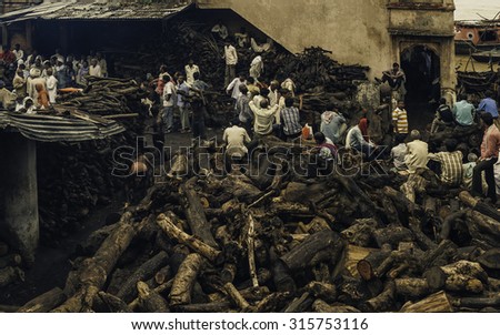 VARANASI, INDIA - AUGUST 13, 2011: Men bargain to buy wood for Hindu cremation ceremony in a crowed yard piled high with wood on bank of Ganges river on August 13, 2011 in Varanasi, India.