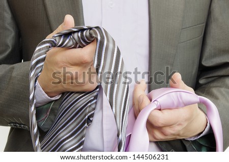 suited man is choosing between two ties which one to wear