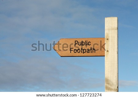Wooden Public Footpath sign against a clear blue sky.