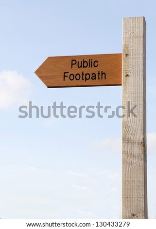 Wooden Public Footpath sign against a partly cloudy sky.