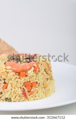 Homemade seafood fried rice with vegetables, shrimp and fish cracker served on a plate.