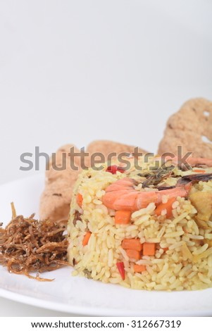 Homemade seafood fried rice with vegetables, shrimp and fish cracker served on a plate.