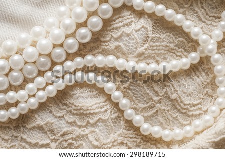 Pearl necklace on lace clothes background.