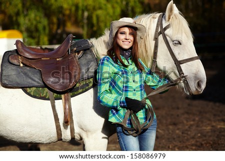 cute smiling cowgirl in a hat with a white horse