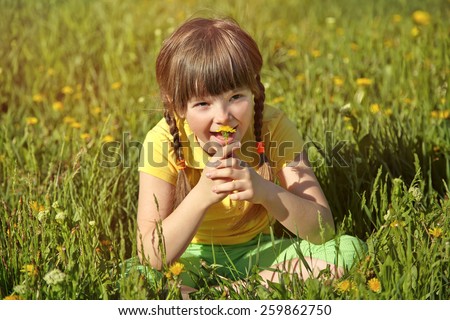 little girl sitting in the grass with dandelion in her hands. summer child outdoors