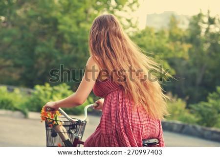 young woman in a dress rides a bike in a summer park. Active people. Outdoors